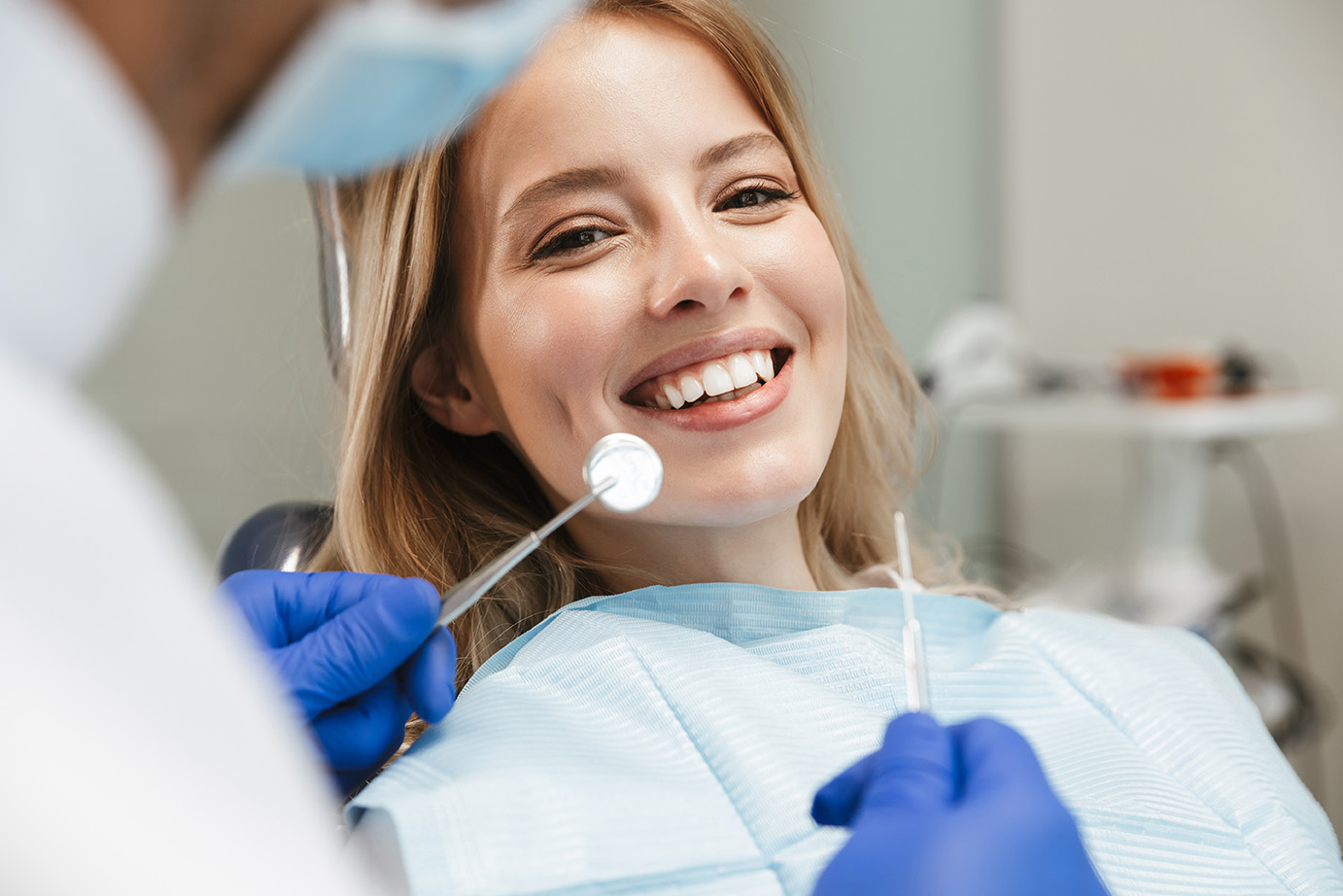 Image of satisfied woman sitting in dental chair while professio